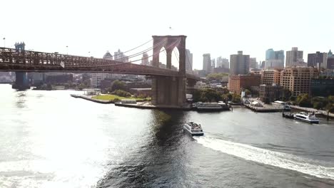 Vista-aérea-de-Nueva-York,-América.-Zánganos-sobrevolando-el-río-East,-barco,-montar-a-caballo-a-través-del-agua,-bajo-el-puente-de-Brooklyn