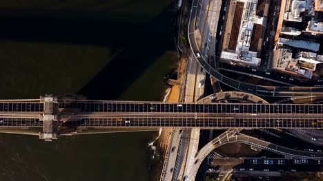 Aerial-top-view-of-Brooklyn-bridge-through-the-East-river-and-road-junction-on-Manhattan-side-in-New-York,-America