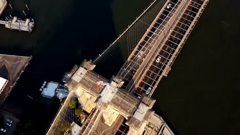 Aerial-top-view-of-Brooklyn-bridge,-with-American-flag-on-it.-Scenic-view-of-East-river-in-New-York,-America