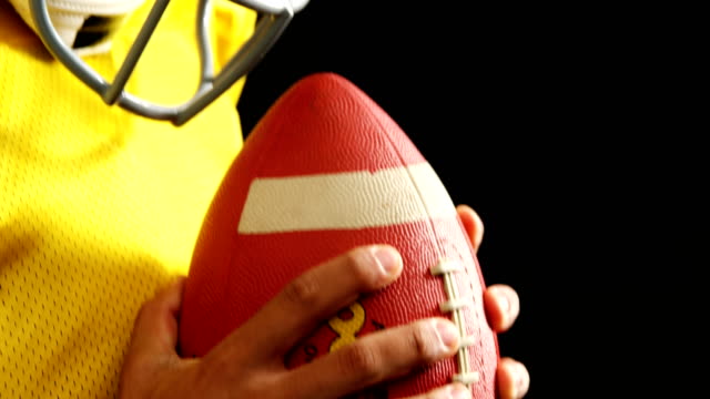 American-Football-Spieler-mit-Ball-vor-schwarzem-Hintergrund-4k