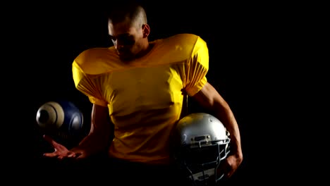 US-amerikanischer-Footballspieler-holding-Kopfbedeckung-und-jonglieren-Ball-4k