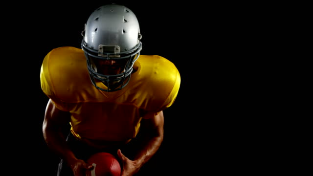 American-football-player-leaning-forward-holding-a-ball-4k