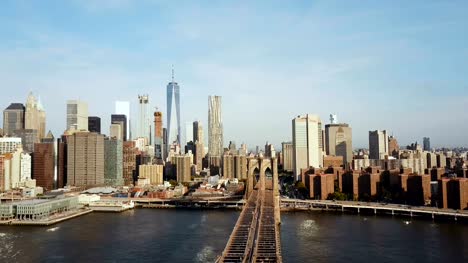 Vista-aérea-del-puente-de-Brooklyn-con-la-bandera-americana-ondeando-en-el-viento.-Vista-panorámica-del-río-del-este,-Manhattan-en-Nueva-York