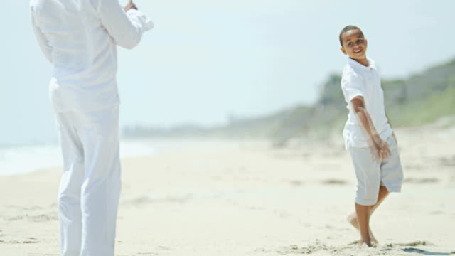 Son-and-dad-playing-American-football-on-beach