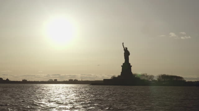 Breite-Schuss-der-Statue-of-Liberty,-gefilmt-in-den-Sonnenuntergang-vom-Fluss-in-New-York,-Vereinigte-Staaten-von-Amerika