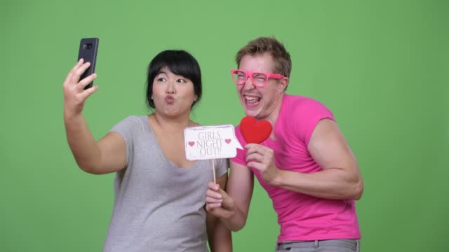 Sobrepeso-mujer-asiática-y-joven-gay-tomando-selfie-juntos