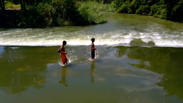 jungen,-die-zu-Fuß-in-Wasser-im-Stausee-mit-Fischen-nach-Fische-fangen