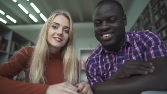 African-american-male-and-european-female-talk-to-camera-in-the-library