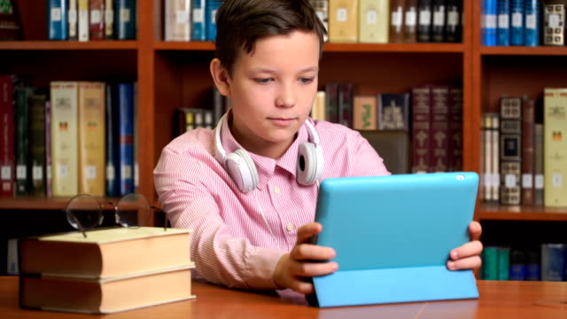 cute-schoolboy-using-computer-tablet-and-listening-to-it-lecture.