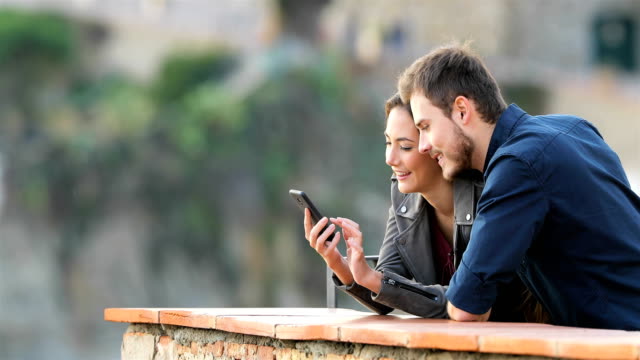 Happy-couple-checking-phone-content-in-a-balcony