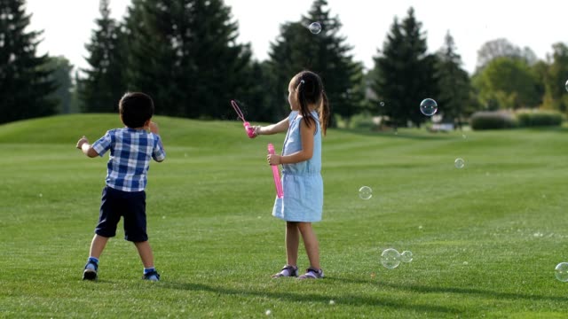 Excited-asian-siblings-having-fun-with-soap-bubbles