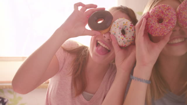 Teenager-Mädchen-mit-bunten-Donuts-auf-Ihre-Augen