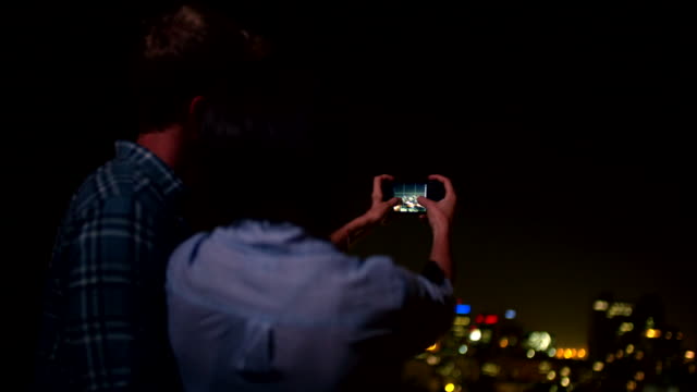 Happy-couple-taking-picture-of-the-city-from-the-rooftop