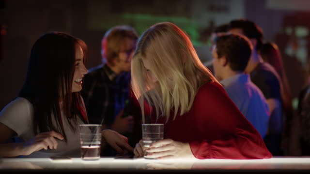 Dos-atractivas-chicas-en-el-bar-en-Club-hablando-y-Riendo