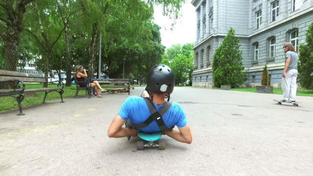 Cool-guy-longboarding-lying-down,-having-fun-with-friends