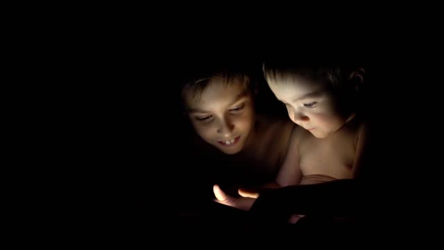 Two-young-brothers-playing-with-tablet-at-night.-4K