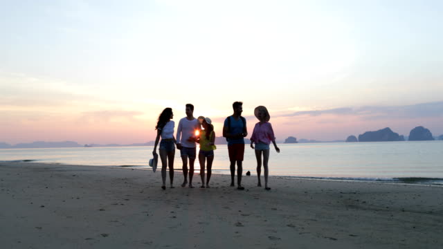 Menschen,-die-am-Strand-bei-Sonnenuntergang-wandern,-junge-Touristen-Gruppenkommunikation