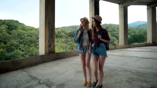 Two-pretty-girls-young-women-friends-travelers-walk-outdoors-on-mountain-scene