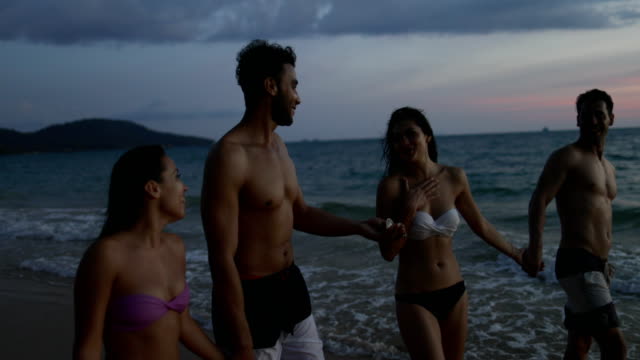 Gruppe-von-Freunden-am-Strand-bei-Sonnenuntergang-POV-sprechen,-junge-Menschen-glücklich-lächelnde-Spaziergang-am-Meer-in-den-Sommerferien-am-Meer
