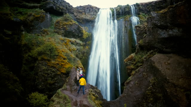 Aerial-view-of-the-group-of-tourists-enjoying-the-view-of-Gljufrabui-waterfall-in-Iceland.-Friends-happy-after-hiking