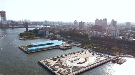 Blick-auf-die-Brooklynbridge-über-den-East-River-zu-Brooklyn-Bezirk.-Drohne-fliegt-über-den-Pier-am-Ufer