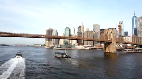 Aerial-view-of-Brooklyn-bridge-going-to-Manhattan-in-New-York,-America.-Drone-fly-under-the-bridge-through-East-river