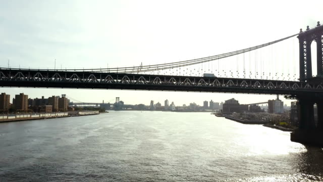 Aerial-view-of-Brooklyn-bridge-through-the-East-river-in-New-York,-America.-Drone-flying-under-the-road-on-the-bridge