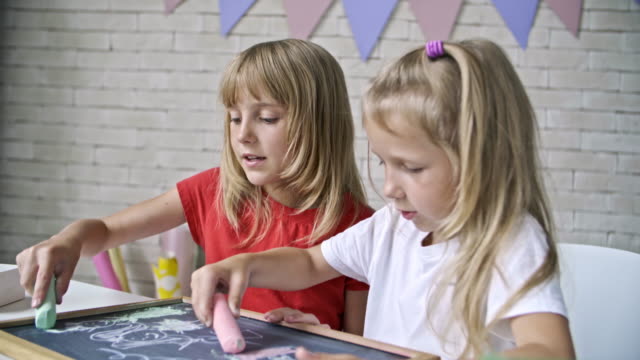 Niedlichen-Mädchen-zeichnen-mit-Kreide-auf-die-Tafel