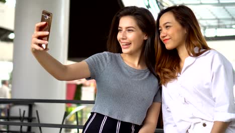 Two-happy-girls-talking-selfie-with-smartphone