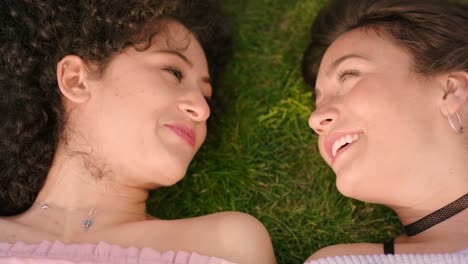 Two-young-woman-laying-on-the-meadow-laughing