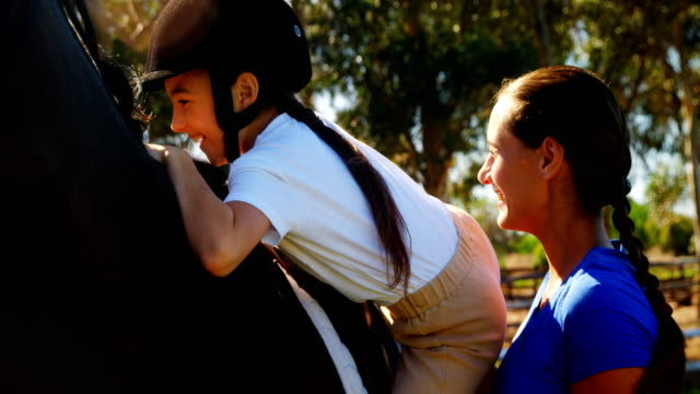 Mother-assisting-daughter-during-horse-riding-4k