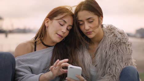 Zwei-attraktive-Mädchen-Lesen-eines-Artikels-auf-einem-Smartphone-an-einem-sonnigen-Tag