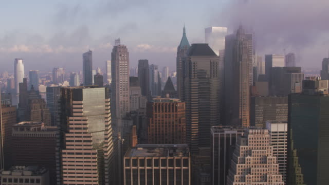 Verfolgung-durch-niedrigere-Manhattan-Gebäude-mit-niedrigen-Wolken-und-Sonne-am-frühen-Morgen.