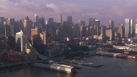 Fliegen-auf-Hudson-River-bei-Sonnenaufgang-mit-Manhattan-Gebäude-und-Piers.