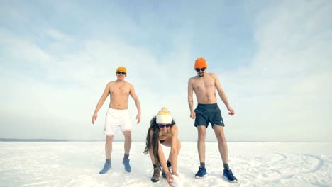 Three-friends-play-with-winter-snow-while-wearing-swimsuits.