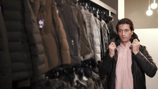 a-young-man-chooses-a-jacket-in-a-clothing-store,-he-tries-on-a-sample-for-himself