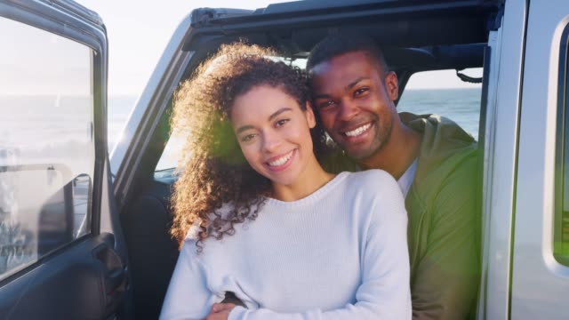 Young-mixed-race-couple-embracing-by-car,-close-up