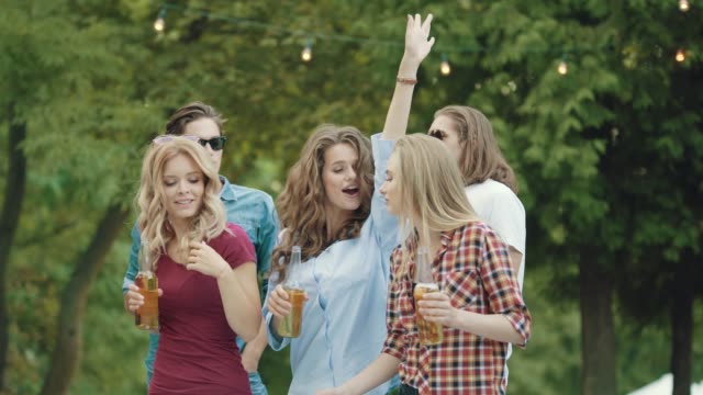 Happy-Friends-Taking-Photos-While-Dancing-And-Drinking-Outdoors.