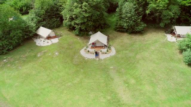 Aerial-view-of-couple-standing-in-front-of-sitting-area-at-a-camping-site.