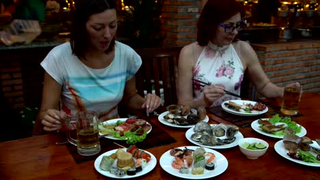 Freunden-an-einem-Tisch-im-Restaurant-Essen-Meeresfrüchte-sprechen-Clink-Becher-Bier-und-Getränke