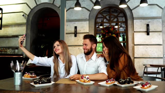 Young-woman-taking-selfie-with-friends-in-restaurant