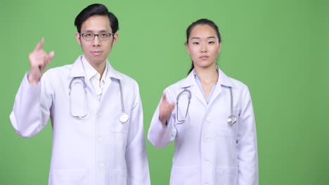 Young-Asian-couple-doctors-pointing-up-together