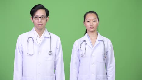 Médicos-de-la-joven-pareja-asiática-con-gesto-de-parada-junto