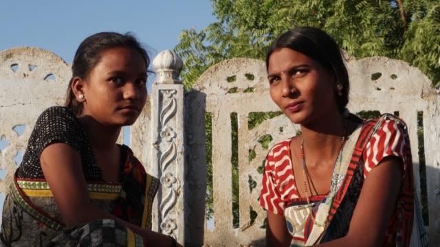Zwei-Weibchen-Blick-auf-Kamera-von-Angesicht-zu-Angesicht-sprechen-Anteil-sitzen-auf-der-Terrasse-heißen-Tag-indischen-Rajasthan-Kleid-traditionelles-Dorf-Sari-Kostüm-zwei-mittlere-erschossen-handheld-closeup