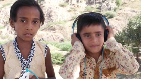 Ein-Kind-über-Kopfhörer-Musik-hören,-während-der-andere-das-Handy-mobile-hält