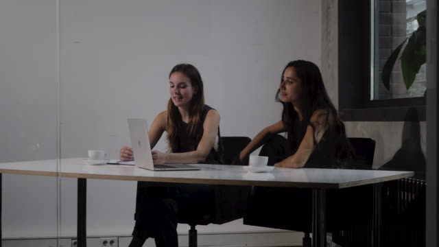 Junge-Frauen-sitzen-nebeneinander-in-einer-Büroumgebung-zu-sprechen