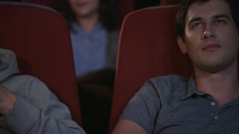 Cerca-de-las-caras-de-gente-joven-viendo-la-película-en-el-cine-teatro