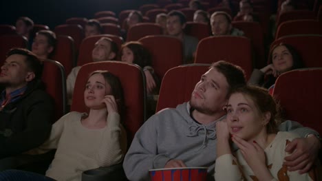 Love-couples-watching-movie-in-cinema.-Young-couple-embracing-in-movie-theater