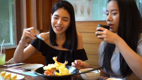 Zwei-asiatische-Freundinnen-Essen-und-mit-einer-Mahlzeit-zusammen.-Frauen-genießen-gute-Zeit-im-japanischen-restaurant