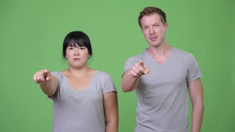 Young-multi-ethnic-couple-pointing-at-camera-together